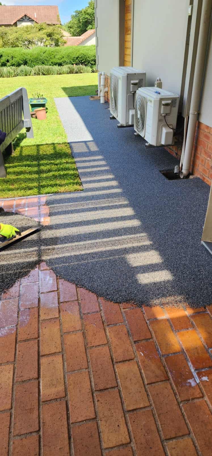 Grey and white pebbles being applied over brick
